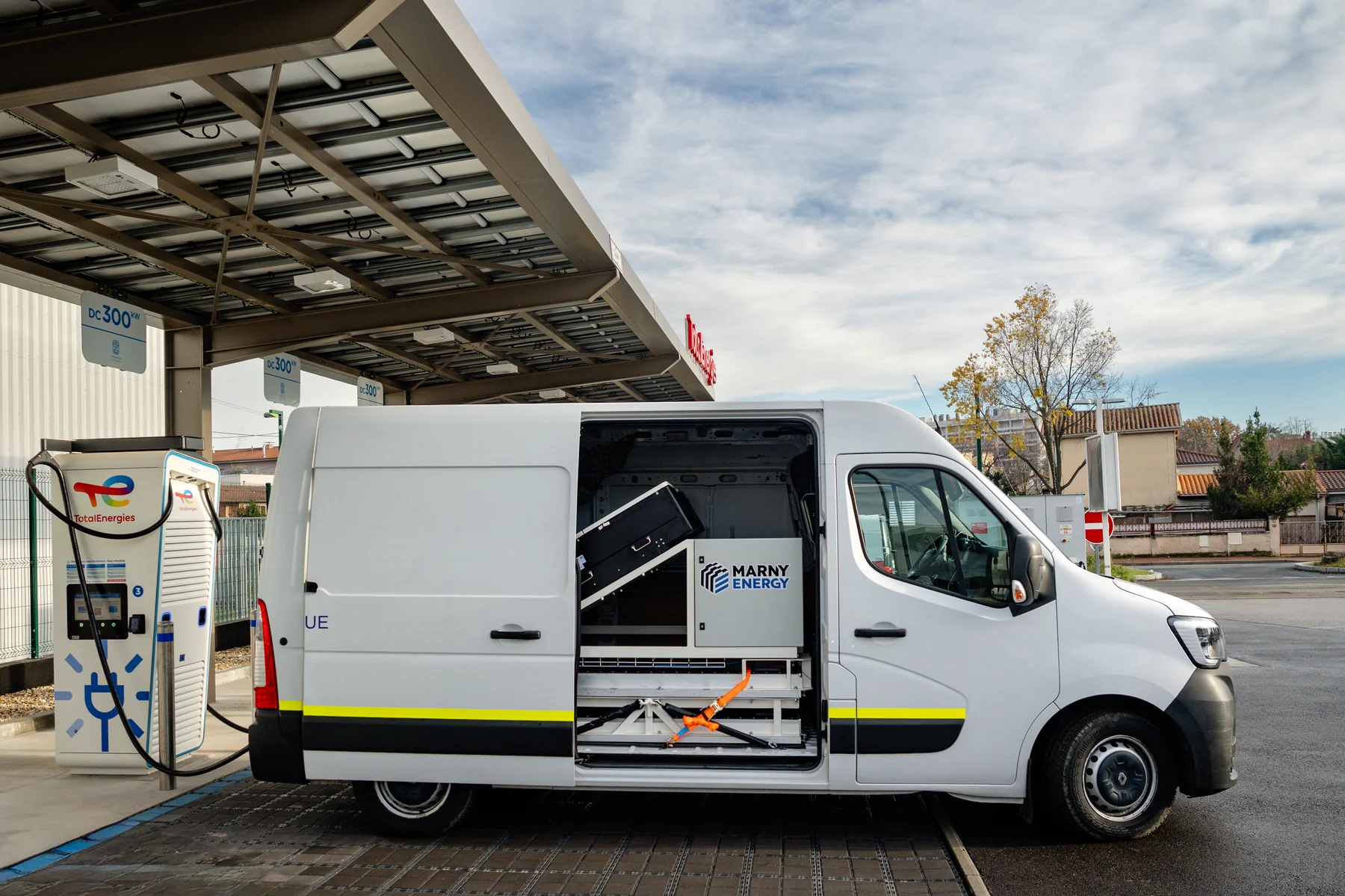 Le stockage Marny Energy intégré dans un fourgon Renault Master blanc, porte latérale ouverte, en charge sur une borne de recharge rapide en courant continu